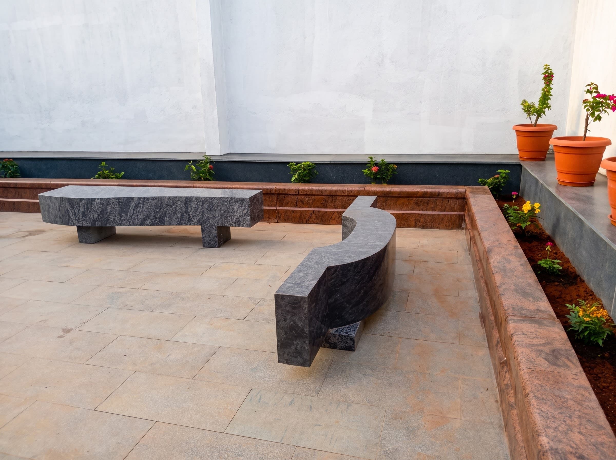 Straight and curved granite garden benches in a planted courtyard