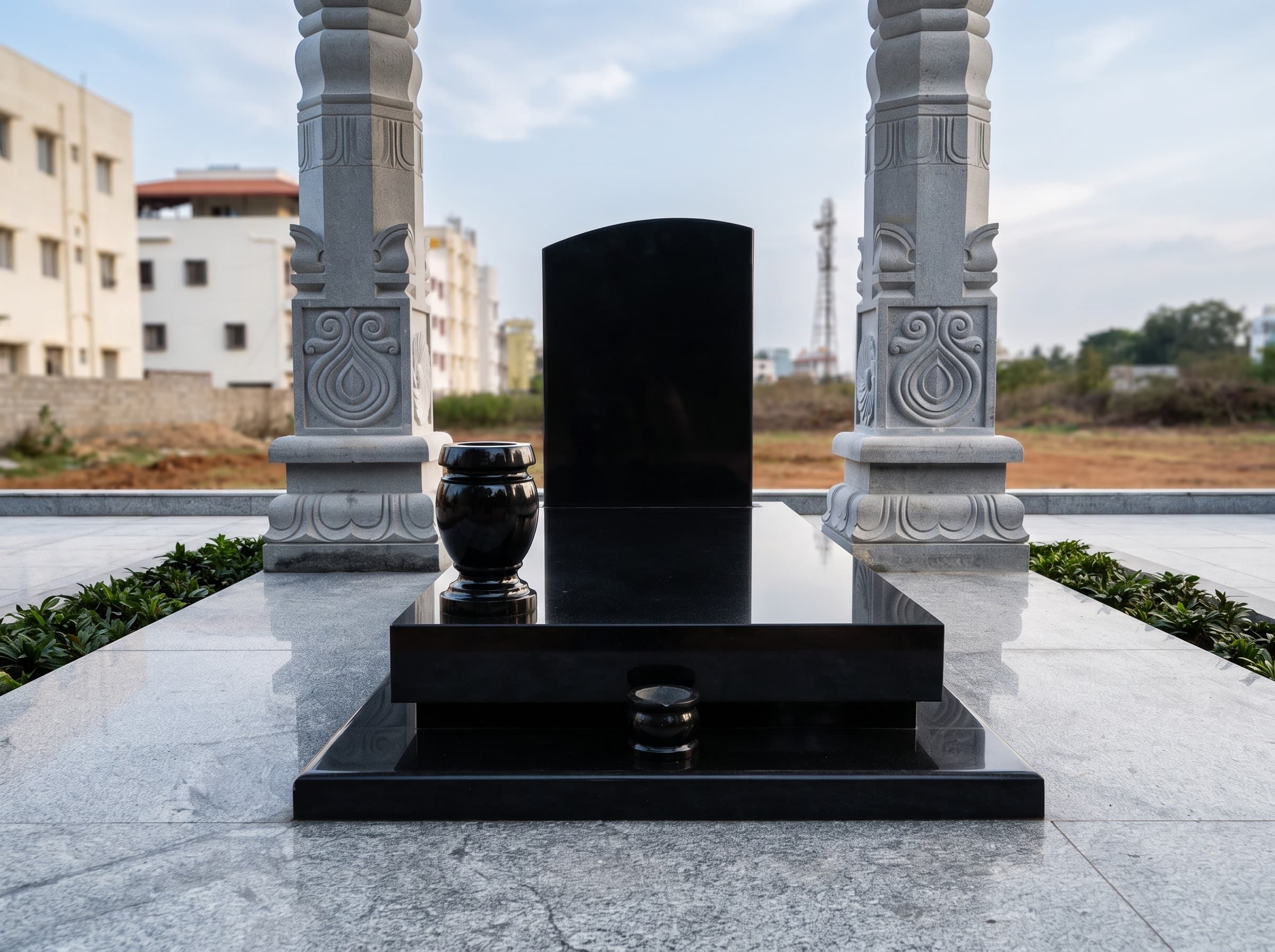 Black granite memorial flanked by two carved white stone pillars