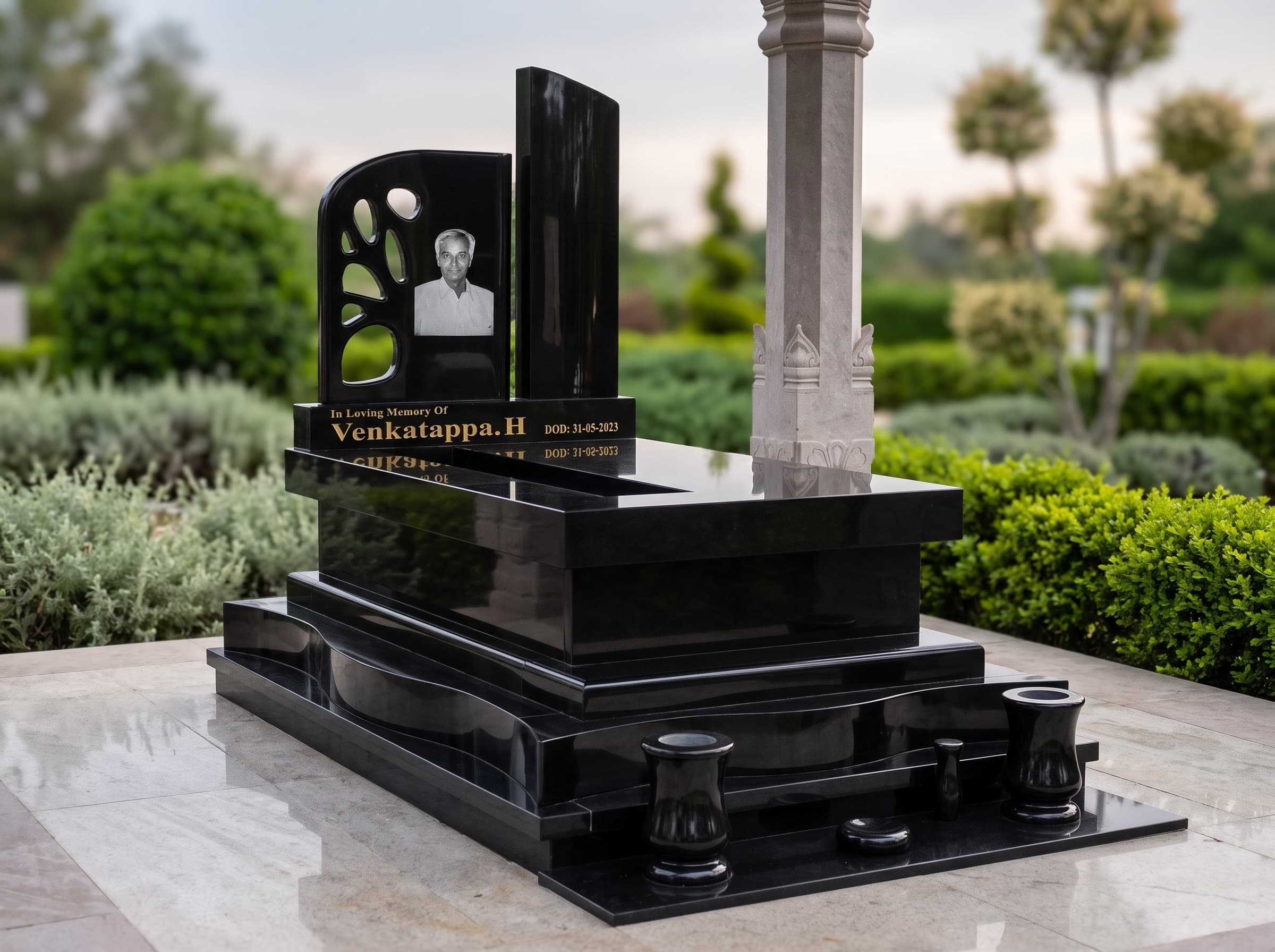 Black granite memorial with an etched portrait, gold lettering and granite urns